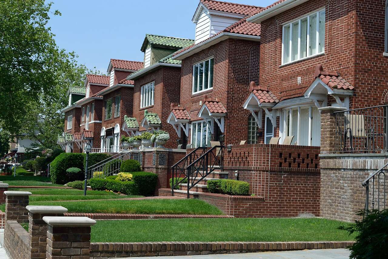 A row of brick houses with shingle roofs along a suburban street