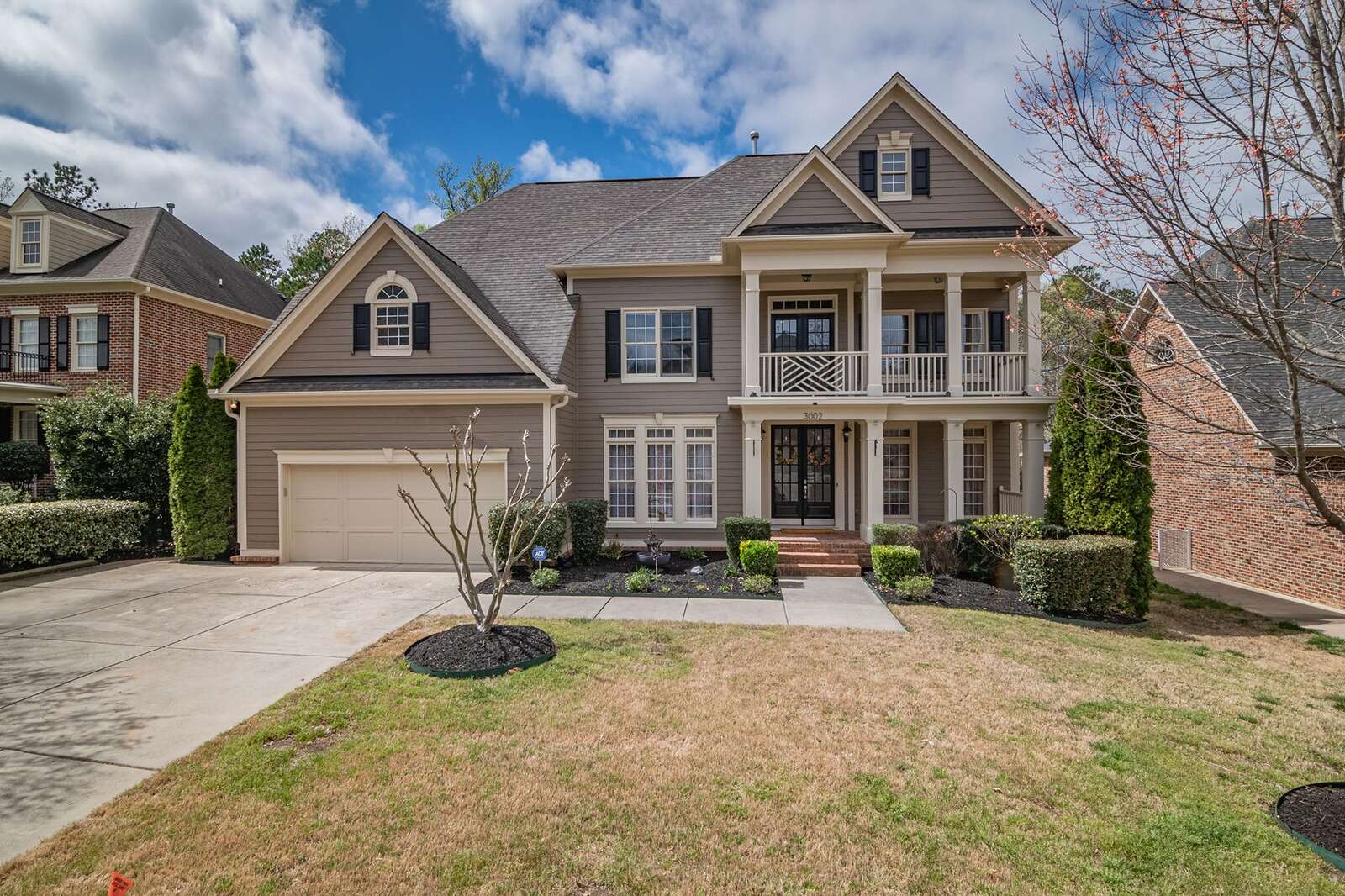 A brick two-story house with a shingle roof and a manicured lawn
