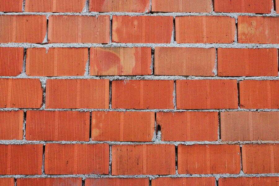 A brick veneer wall close up, the mortar joints and the weep gaps along its base