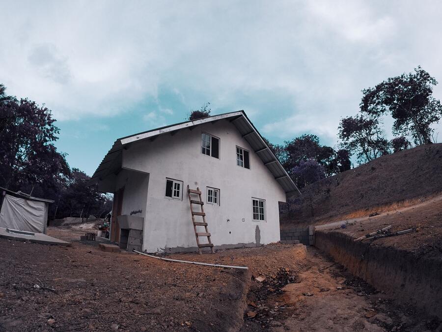 An extension ladder leaning against a house beneath the eave