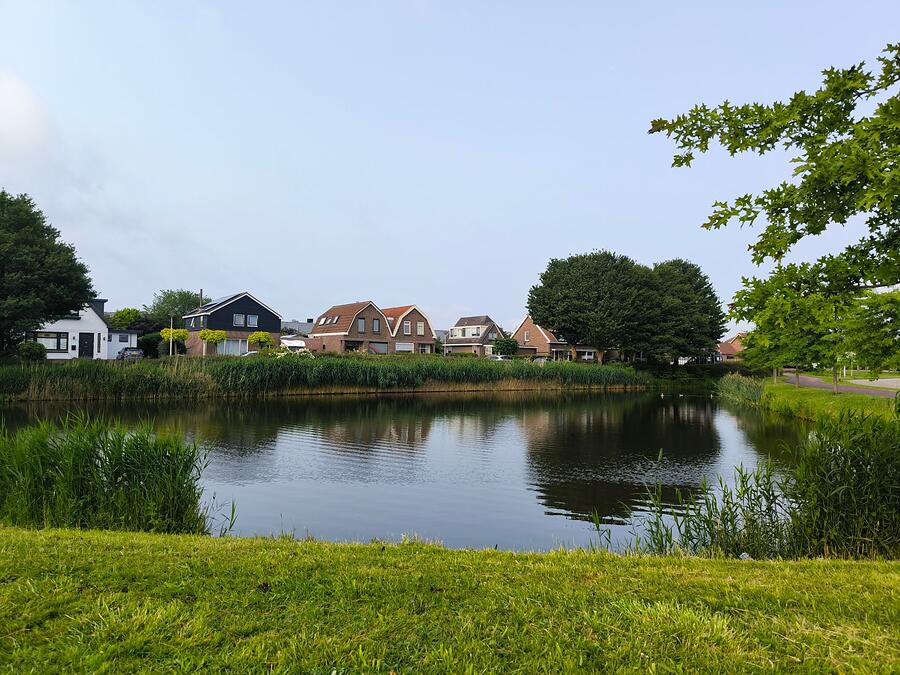 A subdivision detention pond with houses on the far side
